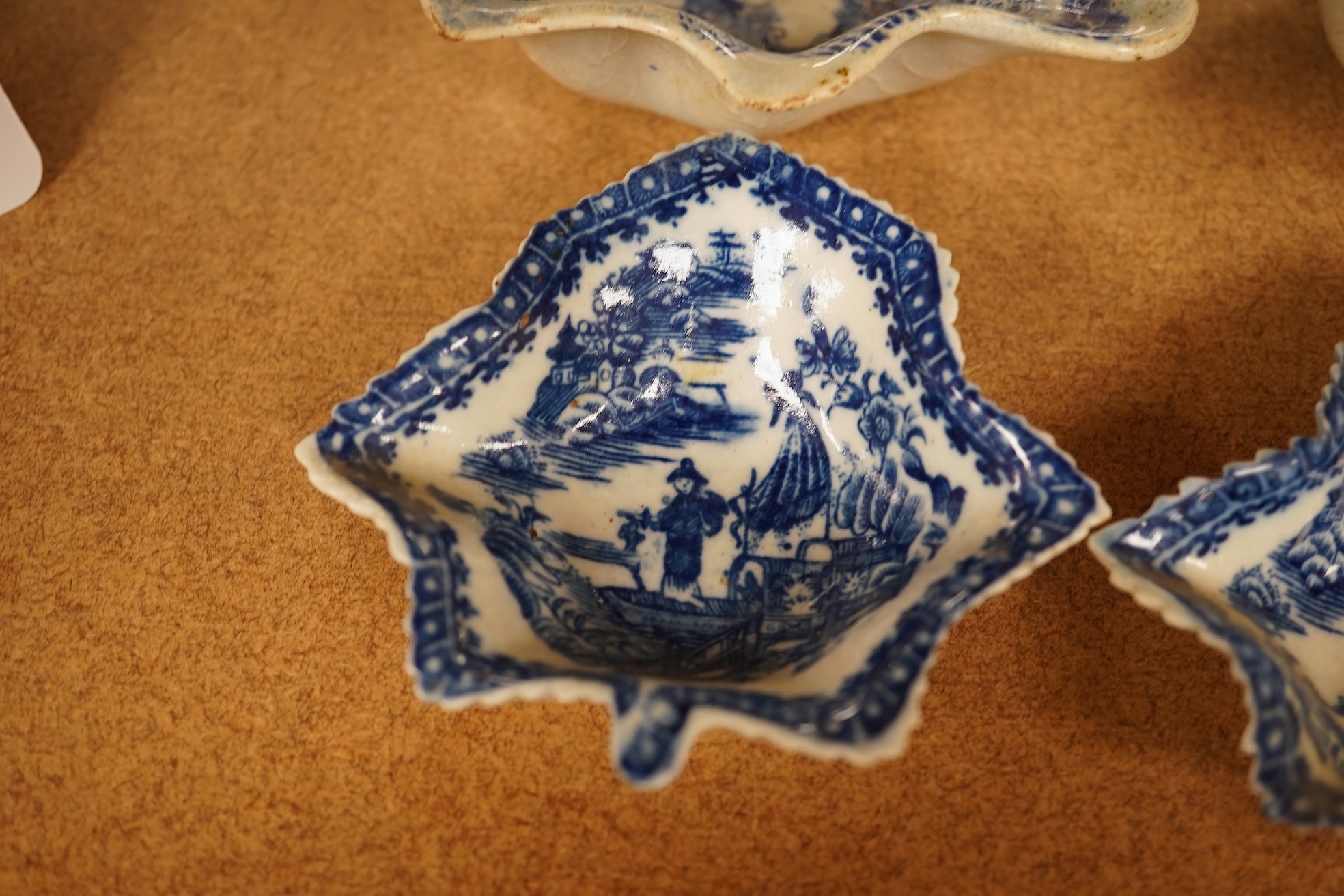 Two late 18th century Worcester or Caughley Cormorant fisherman pattern leaf pickle dishes and two early 19th century blue and white pottery leaf pickle dishes, largest 14.5cm long.